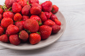 Strawberries on a plate on a white wooden background