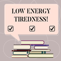 Fototapeta premium Word writing text Low Energy Tiredness. Business concept for subjective feeling of tiredness that has gradual onset Uneven Pile of Hardbound Books and Blank Rectangular Color Speech Bubble