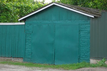 green brick garage with a metal gate and a fence in the street