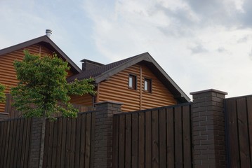 loft of a private wooden brown house with windows behind the fence