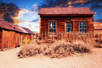 wooden abandoned house in the desert at sunset