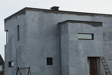 gray concrete unfinished house with small windows against the sky