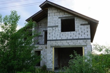 Fototapeta na wymiar white brick unfinished house on a building site in green vegetation