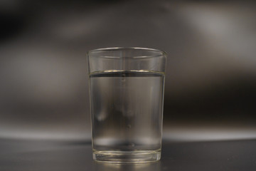 Just a glass of water on a dark wooden table. Mineral water in a glass on a black background. A glass with water