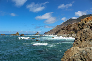 Fototapeta na wymiar Steep high lava rock cliffs. Blue sea horizon, natural sky background.