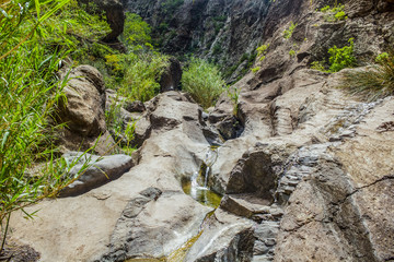 Rocks in the Masca gorge, Tenerife, showing solidified volcanic lava flow layers and arch formation. The ravine or barranco leads down to the ocean from a 900m altitude.