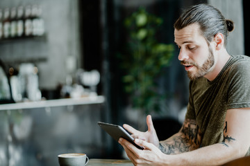 Hipster man Using Tablet Computer Smile Sitting in Cafe Surfing Internet