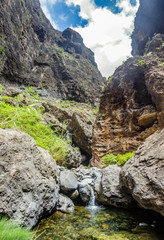 Rocks in the Masca gorge, Tenerife, showing solidified volcanic lava flow layers and arch formation. The ravine or barranco leads down to the ocean from a 900m altitude.