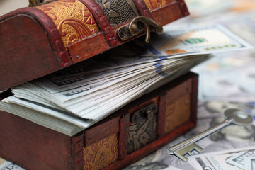 A full chest with dollar bills. Dollars bils background and silver key. Close up