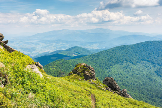 amazing view from the top of a mountain. path through the meadow with huge boulders on the edge. summer landscape with hills of the ridge rolling down in to the mountain. borzhava range on the horizon