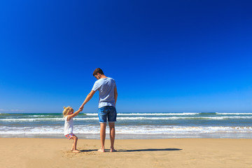 Father and daughter have fun on the seashore.