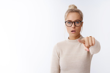 Confused and shocked woman seeing celebrity standing in stupor and frustration pointing at camera...