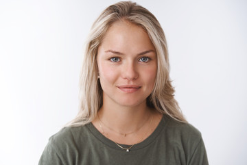 Obraz premium Young attractive adult woman with blond short hair tanned smiling cute and gazing at camera with friendly pleasant attitude expressing caring and tender emotions against white background