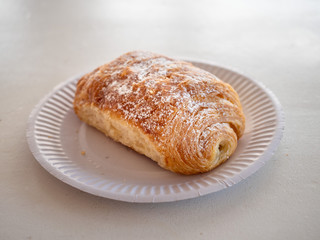 Plain croissant on a white paper plate , Selective focus, One.