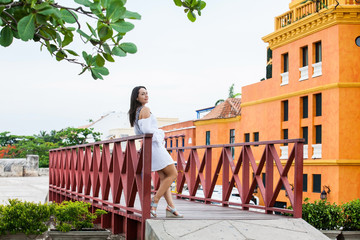 Beautiful woman on white dress standing alone at the walls surrounding of the colonial city of...
