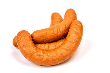 Grilled sausages with onions on a Board on a light background. Juicy sausage rings in a pile on a white background.