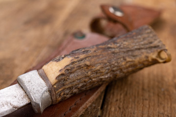 Old little dirty hunting knife on a wooden table. Hunting accessories needed for hunting big game.