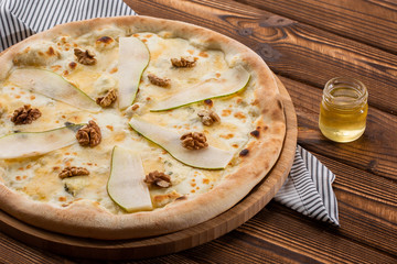 Traditional pizza with pear, nuts and blue cheese on a wooden background. Close up. Top view.