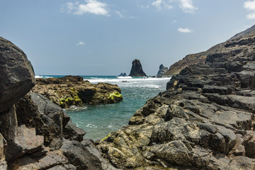 Fototapeta na wymiar Steep high lava rock cliffs. Blue sea horizon, natural sky background.