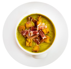 Top view of creamy zucchini soup with croutons and jamon