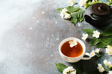 Tea jasmine background with teapot, leaves and flowers on dark texture
