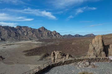 Mountains and lava fields around volcano Teide, partly covered by the clouds. Bright blue sky....