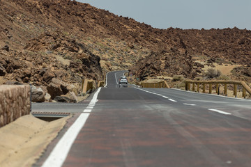 Nearest future. Asfalt road crossing Mars landskape. Mountains around volcano Teide. Bright blue...