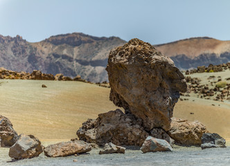 Mountains and lava fields around volcano Teide, partly covered by the clouds. Bright blue sky. Teide National Park, Tenerife, Canary Islands, Spain.