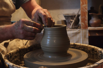 Fototapeta na wymiar hands of potter creating a jar on potters wheel