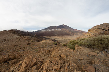 Mountains around volcano Teide, partly covered by the clouds. Bright blue sky. Teide National Park, Tenerife, Canary Islands, Spain.