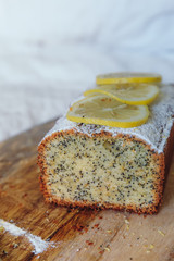 Cake with poppy seeds and lemon zest, sprinkled with powdered sugar. Cupcake with lemon on a wooden board