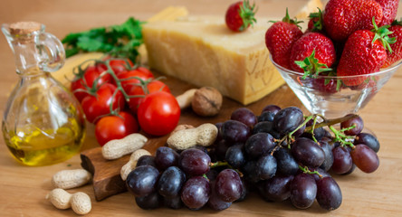 Fototapeta na wymiar Healthy vegan food lunch. Vegetarian dining table. Grapes, tomatoes, spaghetti, cheese, strawberries on a wooden background. copy space