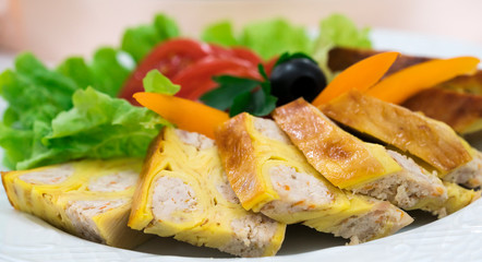 baked meat with dough and vegetables on a white plate