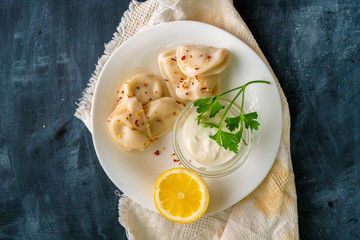 top view of cooked dumplings with lemon and creamy sauce and green herbs