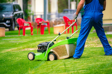 Fototapeta premium gardener worker cutting grass with mower in the backyard lawn fields