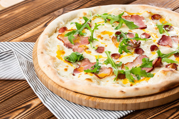 Pizza with ham , arugula (salad rocket), rucola and mozzarella  on  wooden background close up. Italian cuisine.