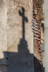 Old wall with shadow of cross statue at cemetery