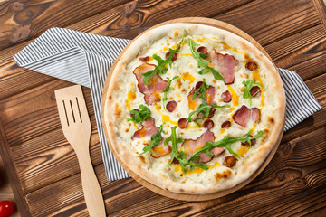 Pizza with ham , arugula (salad rocket), rucola and mozzarella  on  wooden background close up. Italian cuisine.