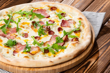 Pizza with ham , arugula (salad rocket), rucola and mozzarella  on  wooden background close up. Italian cuisine.