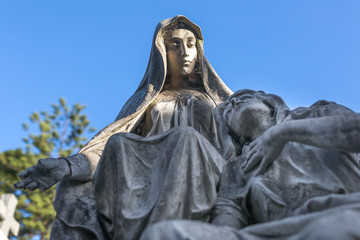 Tomstone statue with mourning ladies at cemetery