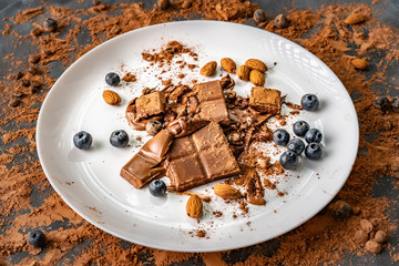 top view of the dessert with chocolate bar, blueberry, almond nuts on the white plates