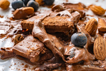 macro shot of a melted chocolate bar with almond nuts and blueberry on the white plates