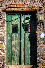 Old Spanish style green door with stone wall and lantern