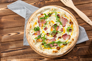 Pizza with ham , arugula (salad rocket), rucola and mozzarella  on  wooden background close up. Italian cuisine.