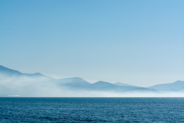 Fototapeta na wymiar Seascape with low fog clouds over sea water in early morning with sun lights