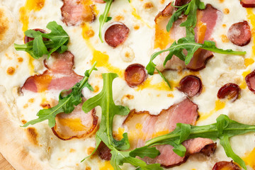 Pizza with ham , arugula (salad rocket), rucola and mozzarella  on  wooden background close up. Italian cuisine.