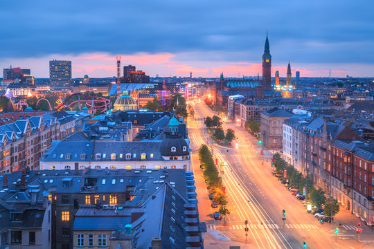 Copenhagen, Denmark cityscape at night - twilight skyline with light trails on H.C. Andersen boulevard and City Hall clock tower in the distance, under blue and pink sky after sunset.