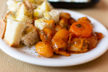 Greek food, cooked white beans with carrot and tomatoes served with roasted with olive oil and herbs bread