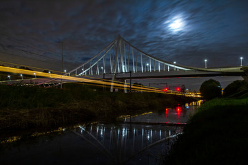 Suspension bridge at night under moonlight with light trails