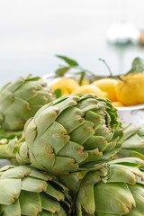 Obraz premium Heads flowers of fresh raw artichokes plants from artichoke plantation in Argolida, Greece ready to cook with lemon